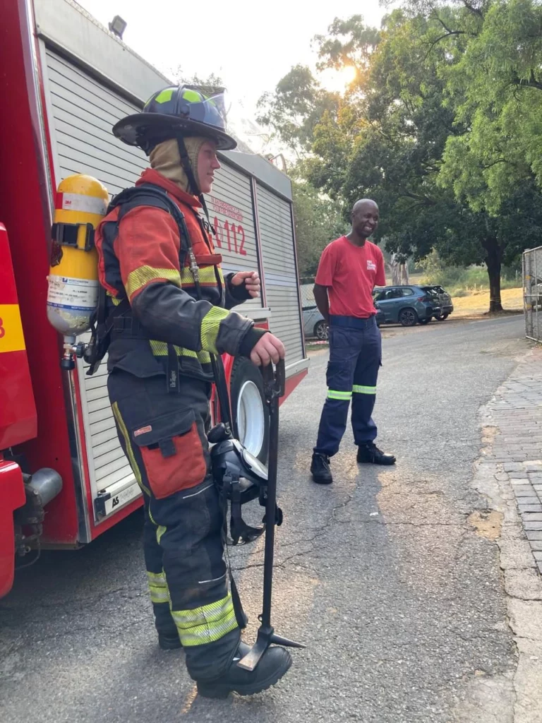 Josh, a first responder in his fire gear standing next to a fire truck.